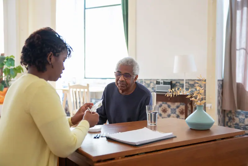 A nurse reviewing a patient's medications with him at a table before discharge