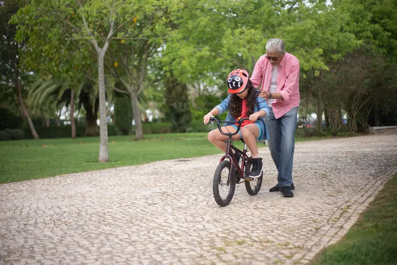 A grandfather teaching his grandson to ride a bike