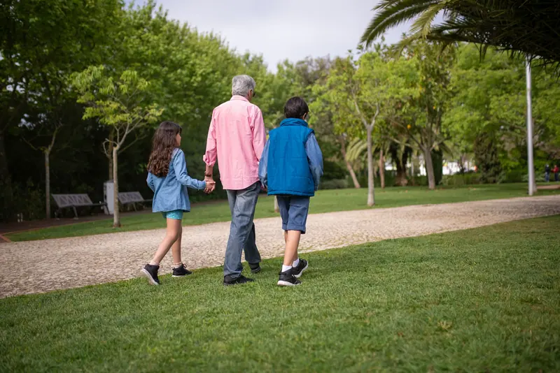 A grandfather walking with his grandchildren on the lawn