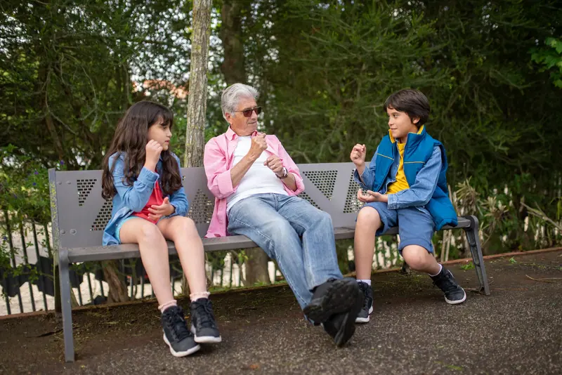 A grandfather on a bench with his grandkids