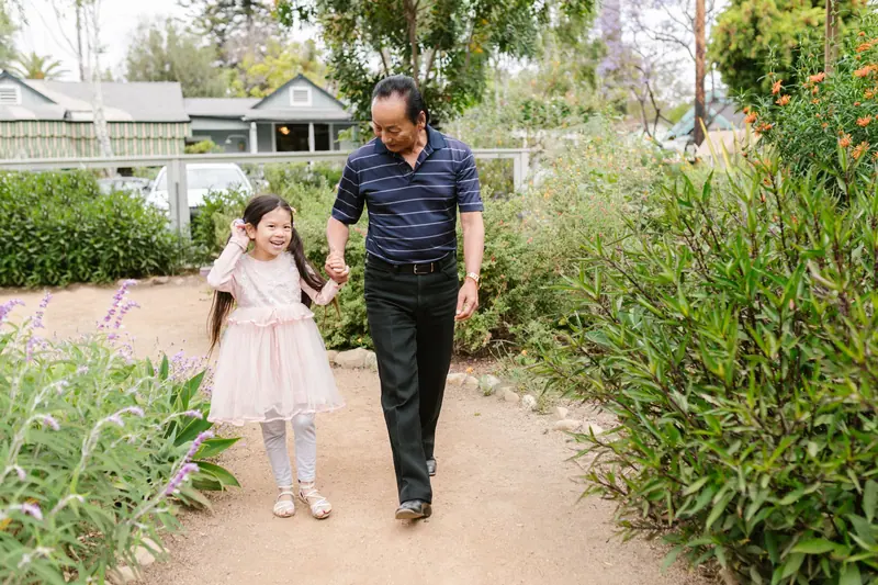 A grandfather walking his granddaughter down the garden path