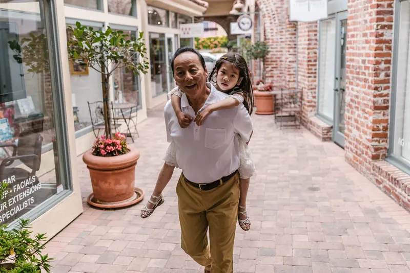 A grandfather walking with his granddaughter past the shops