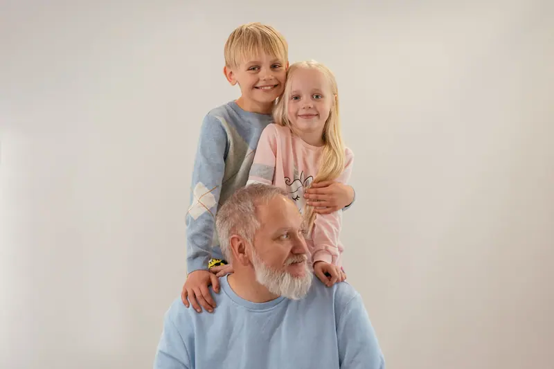 A grandfather with both grandkids hugging his shoulders