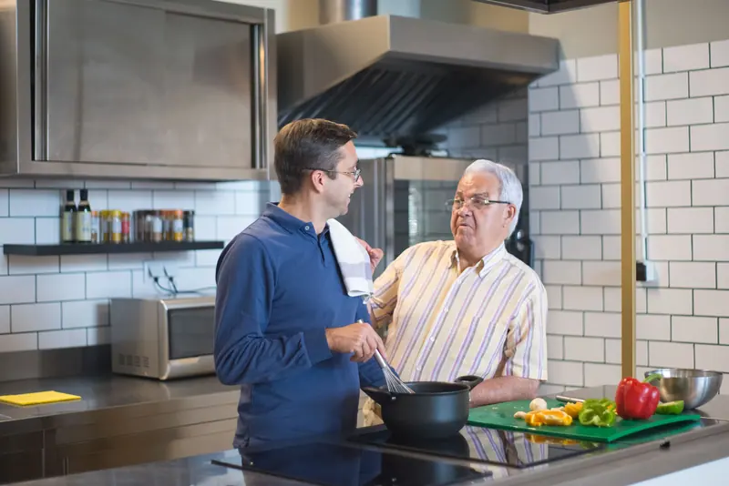 A son and father cooking together after discharge