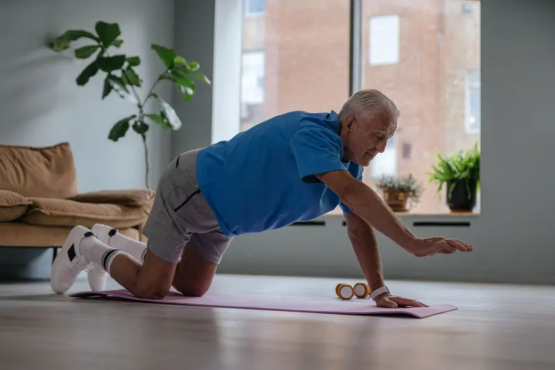 An older man doing a balance exercise on his living-room floor