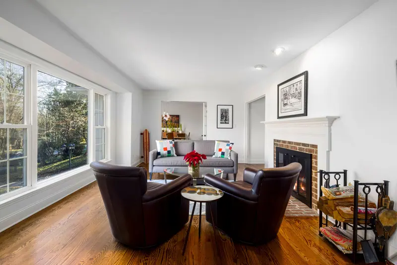 The great room with its fireplace, leather chairs and tall windows