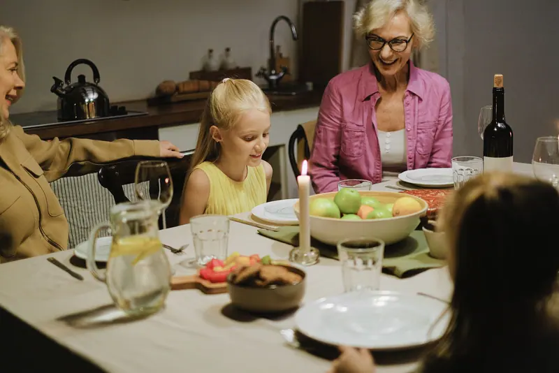 A resident laughing with her granddaughter at supper