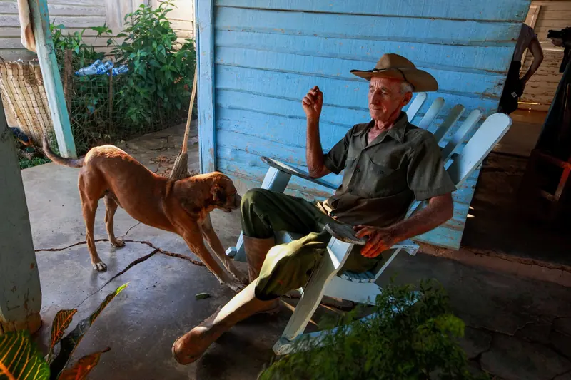 A resident in his hat and boots on the porch, his dog keeping him company