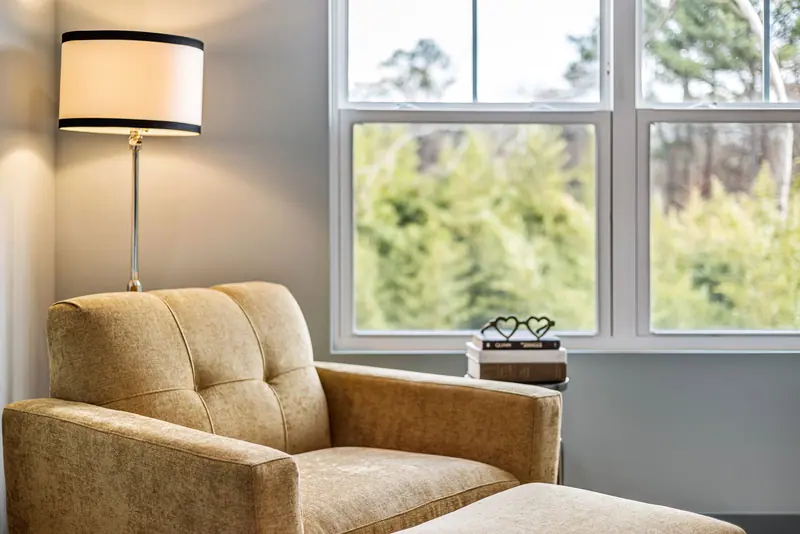 A reading chair and ottoman beside a big window