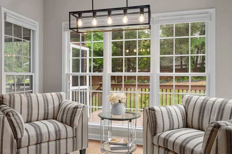 A sitting area with striped armchairs and a garden view