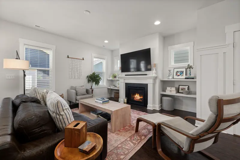 Inviting modern living room featuring a leather sofa, armchair, and a warm fireplace for relaxation.