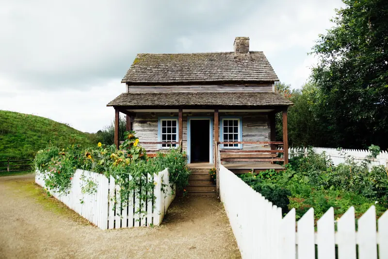 A log cabin with a picket fence near town