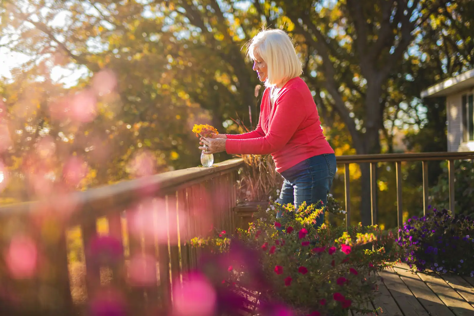 A resident in a red sweater tending the flower boxes on the back deck in golden evening light