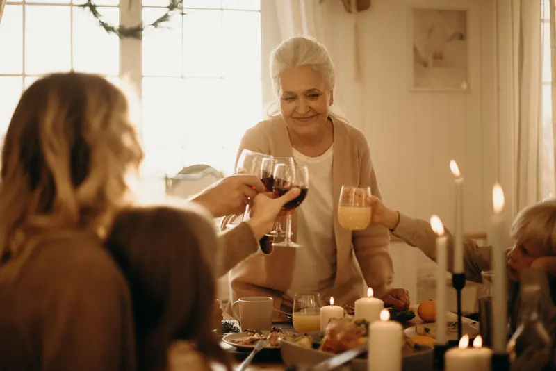 A resident raising a glass with her family at supper