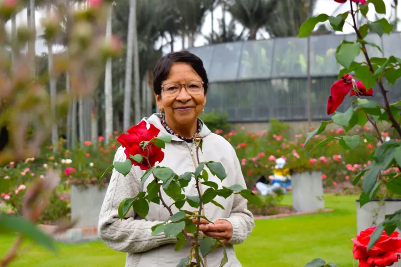 A resident with a fresh-cut rose in the rose garden