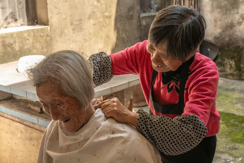 A resident getting her hair trimmed on the patio