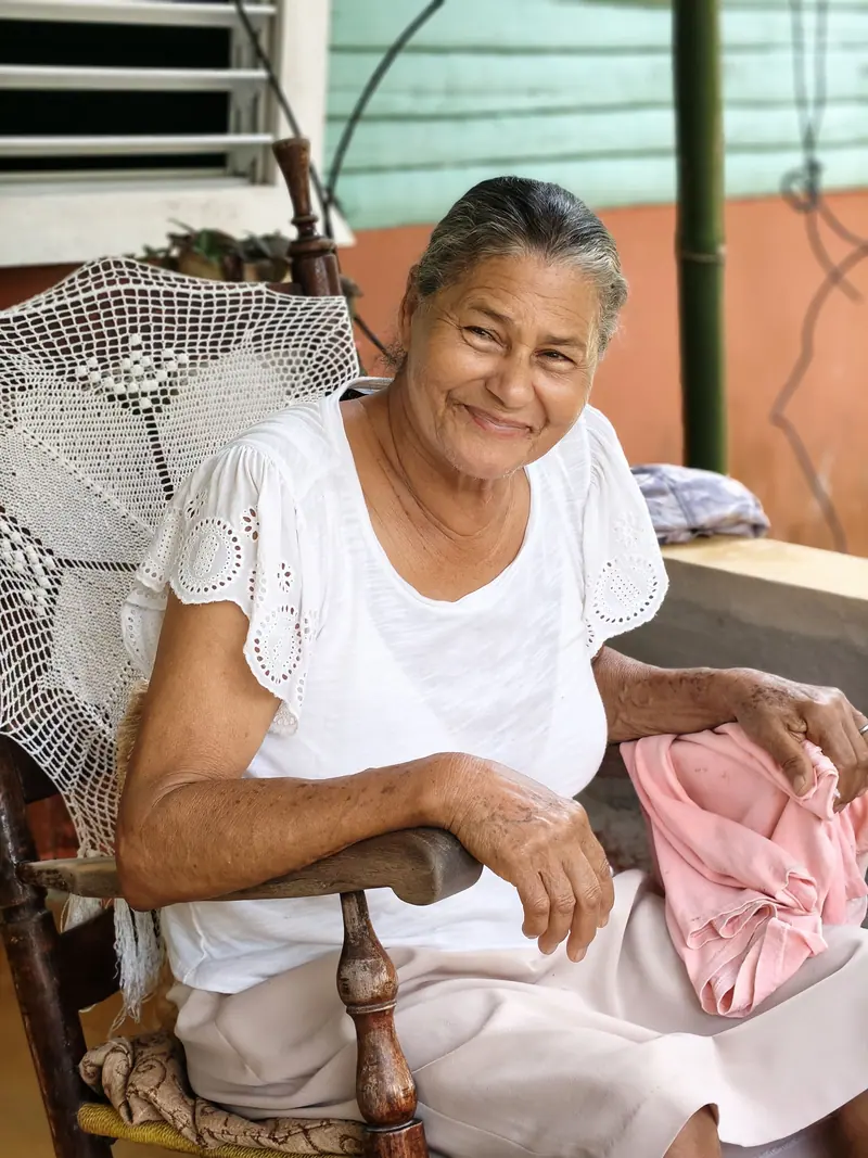 A smiling resident relaxing in a rocking chair on the porch