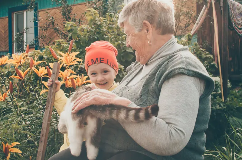 A grandmother and grandson with the neighbor's cat in the garden