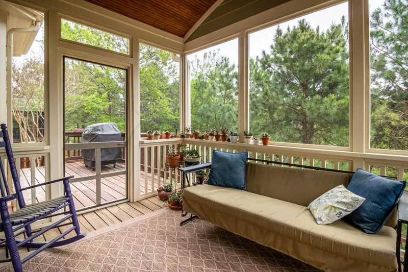 A screened porch with a couch and potted plants