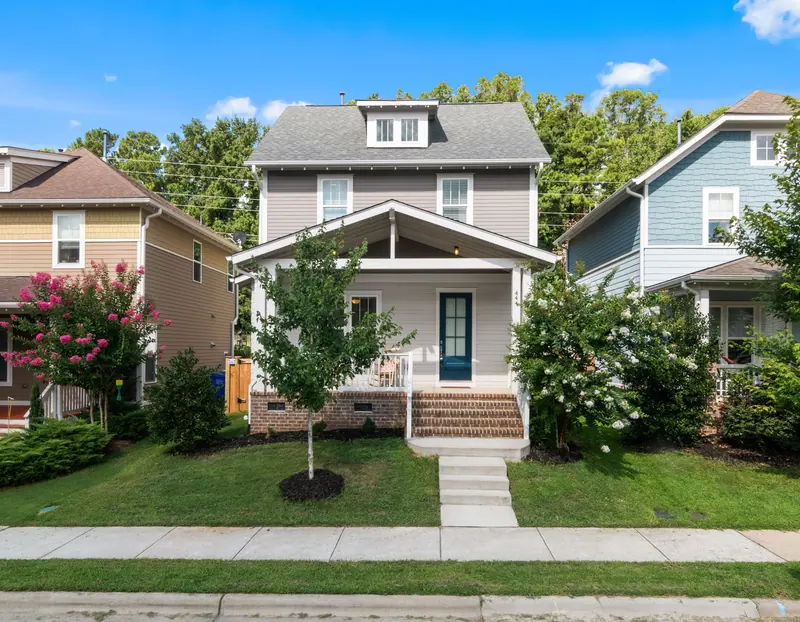 A neighboring foursquare house with a porch and tidy lawn