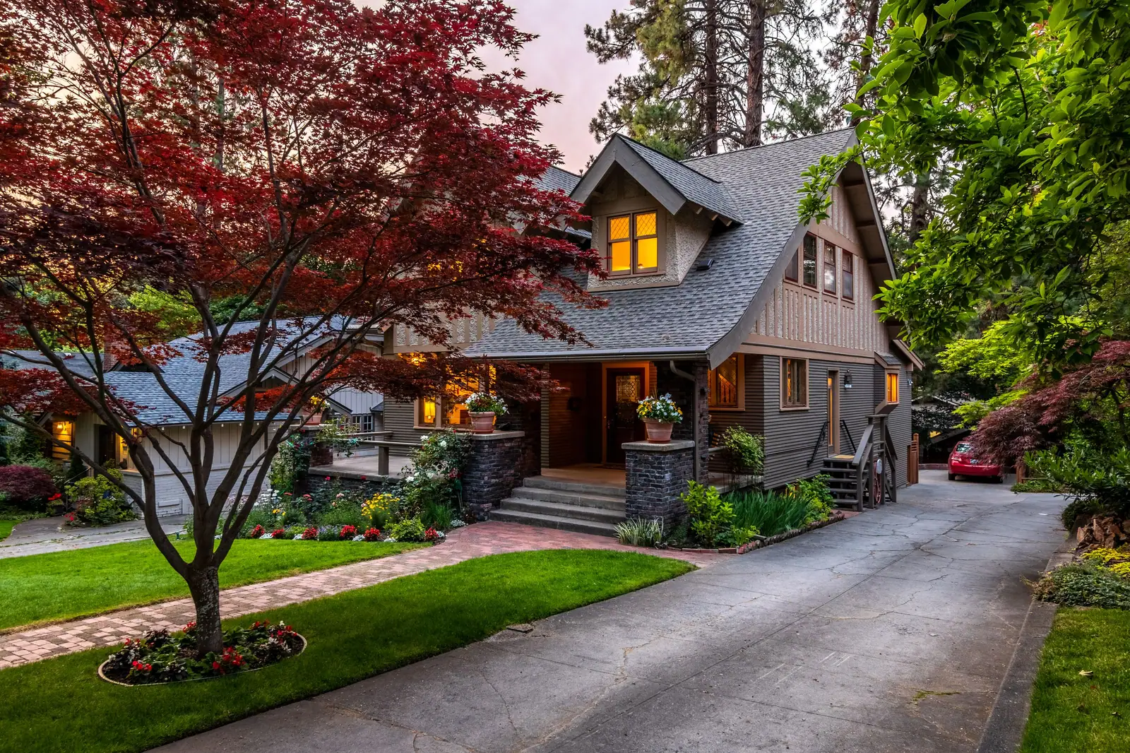 The brick house on Maple Row at dusk, its red maple glowing in the front yard