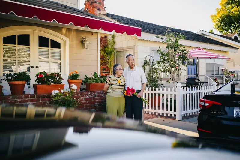 A couple in front of the house holding a bouquet