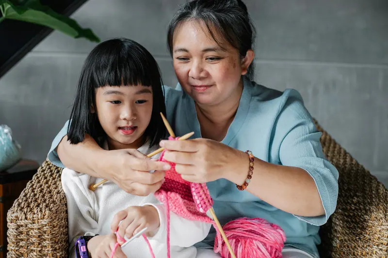 A resident teaching her granddaughter to knit