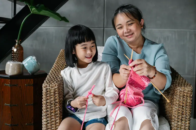 A grandmother teaching her granddaughter to knit