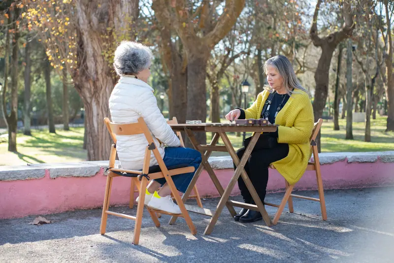 Two residents playing dominoes at the picnic table