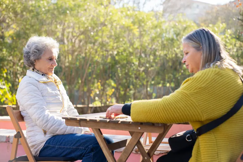 Two residents playing dominoes at the table outside