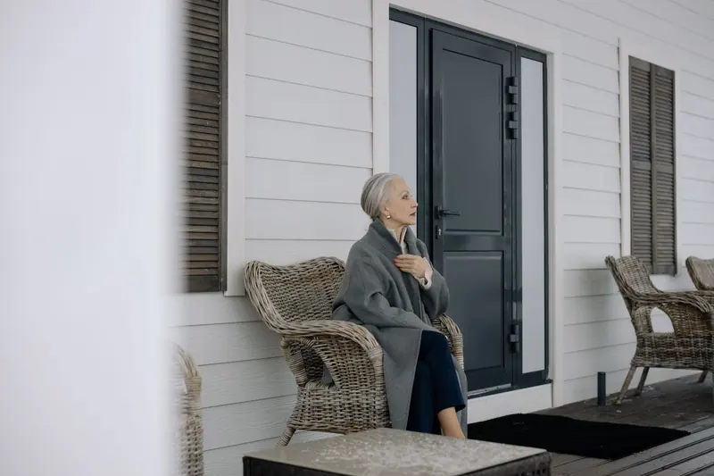 A resident wrapped in a blanket on the porch on a cool morning