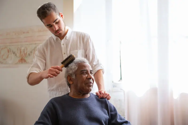 A caregiver combing a resident's hair by the window