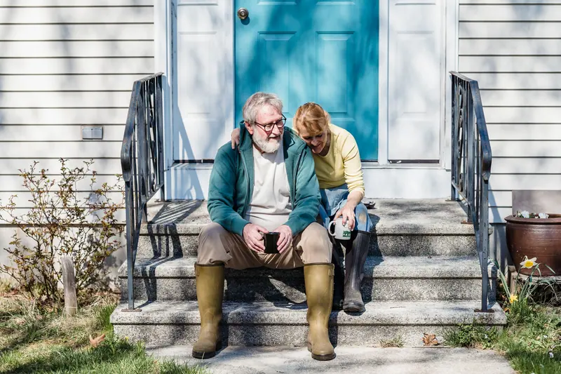 A visiting couple sitting together on the porch steps with their coffee