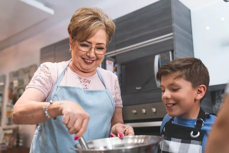 A resident cooking with her grandson in the kitchen