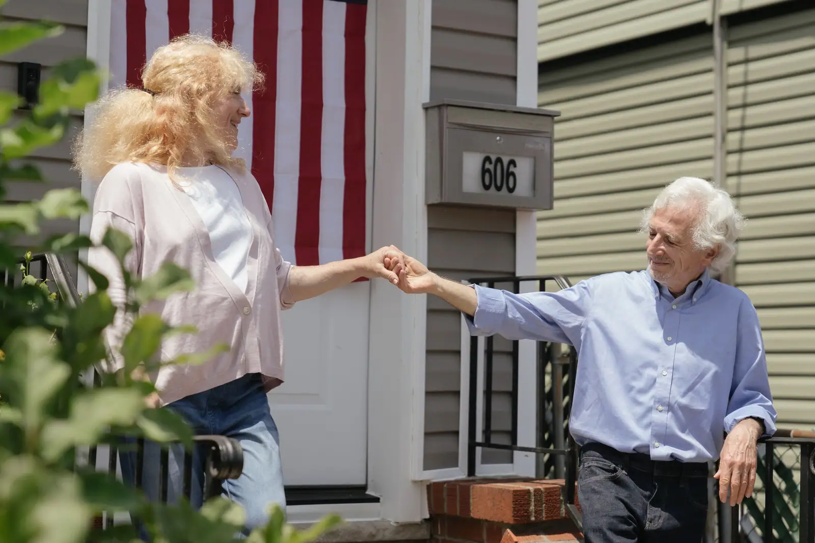 A resident couple holding hands on the front walk on a bright afternoon
