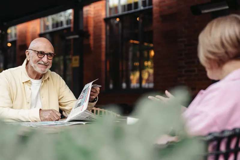 A couple reading the paper together on the back patio