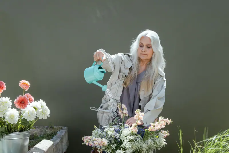 A resident watering flowers in the greenhouse