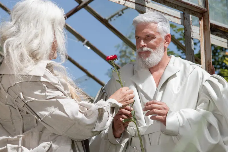 A resident offering a single flower to his wife in the greenhouse