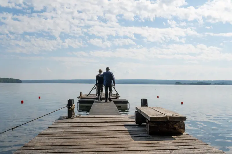 A couple standing at the end of a long wooden pier