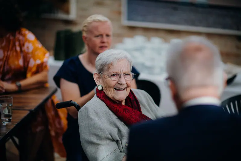 A resident laughing with friends at dinner in the Dockside room