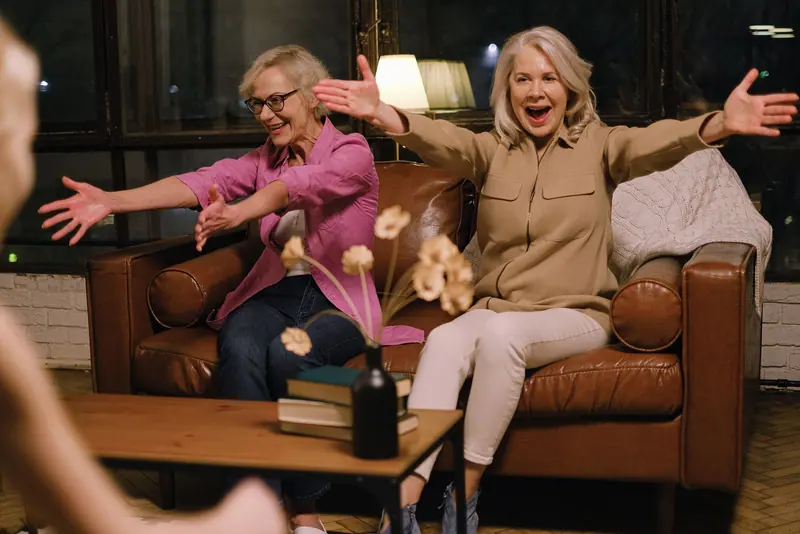Two friends reaching for a hug on the sofa