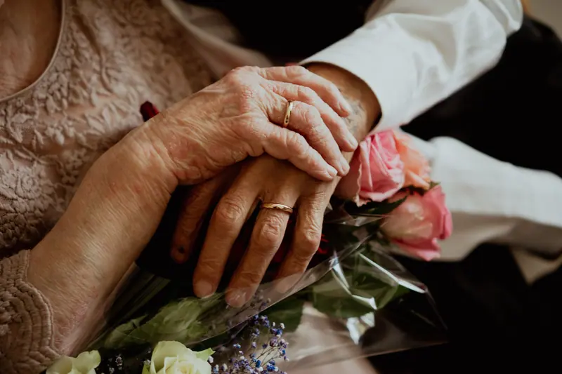 A couple's hands, wedding rings and a small bouquet