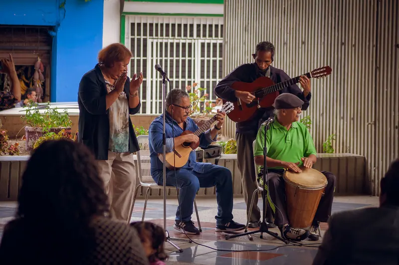 A band of local musicians playing guitars and a drum on the patio