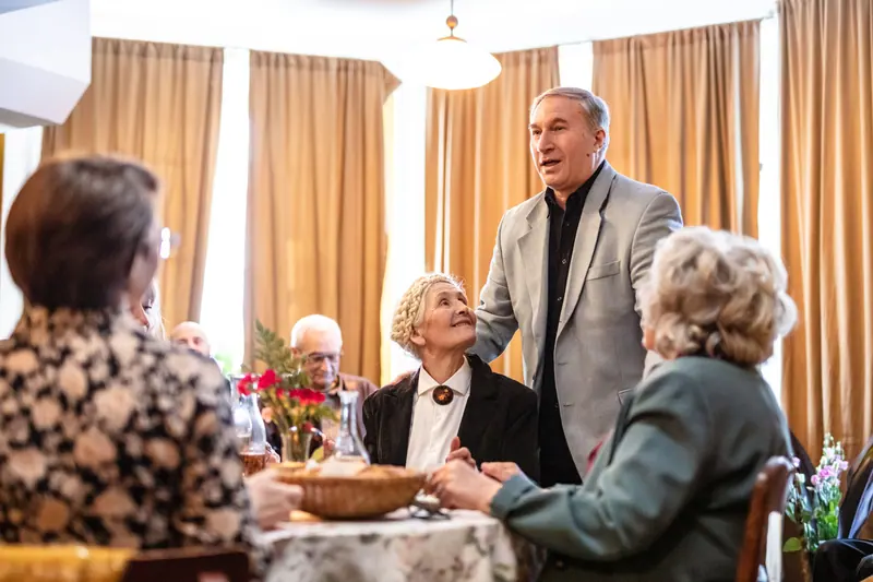 A resident raising a glass during a birthday supper in the dining room