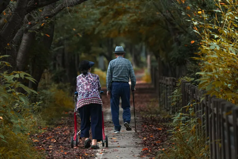 A couple on the shaded trail, her rollator leading the way