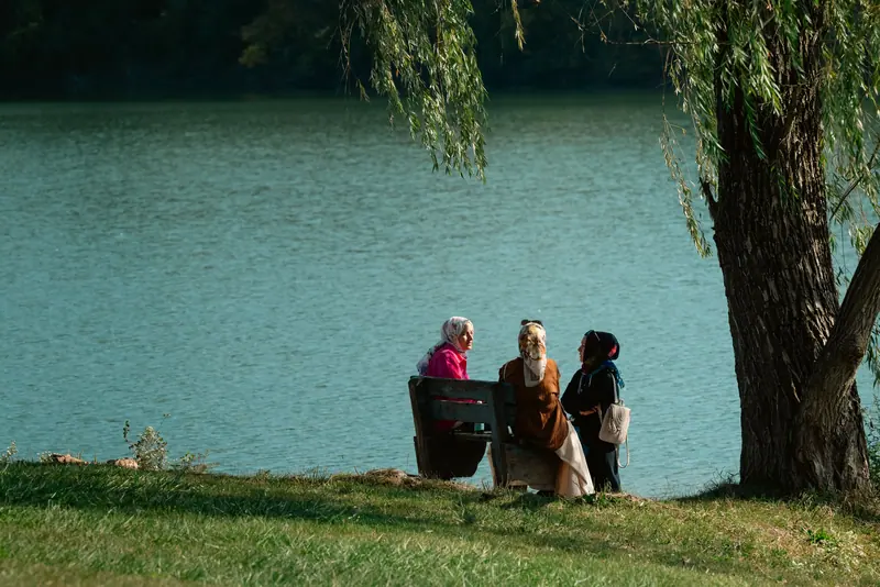 Friends sitting together on the bank under a willow