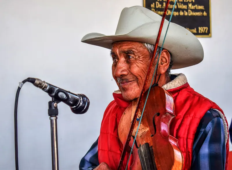 A resident in his cowboy hat playing fiddle at the microphone