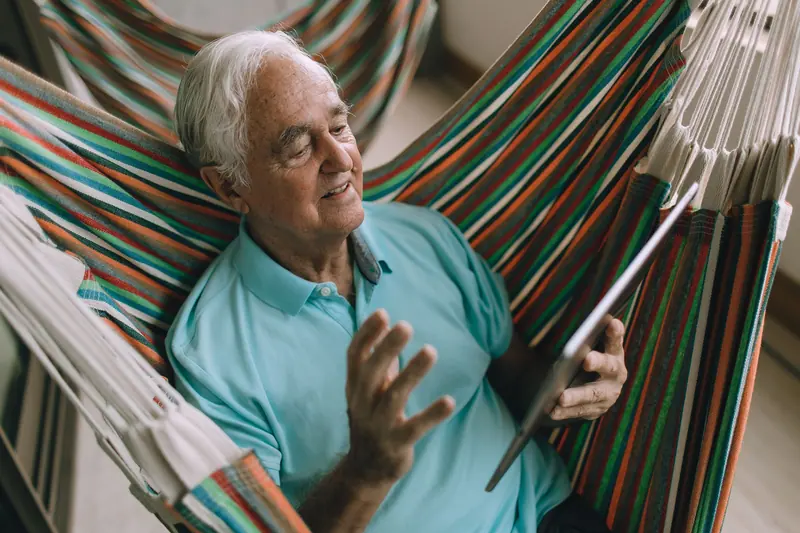 A resident in a hammock video-calling his daughter