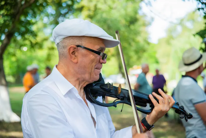 A resident playing violin on the lawn at the fall concert