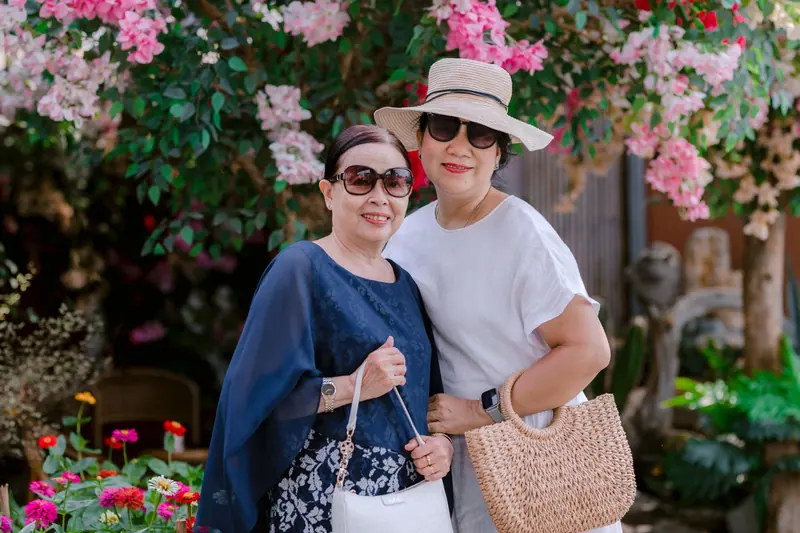 Two residents in sun hats among the flowering shrubs